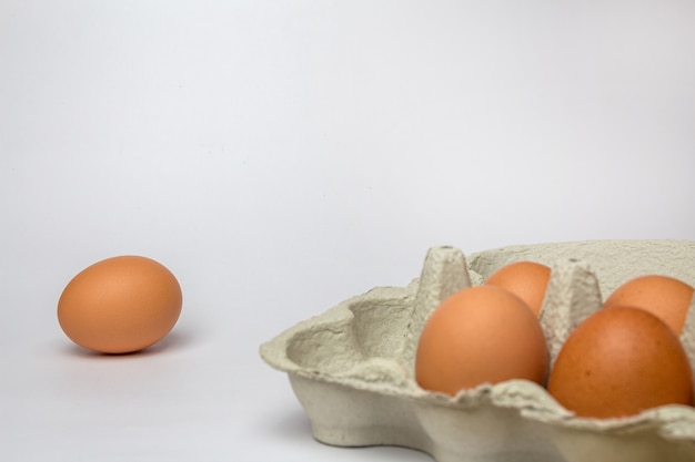 Verse kippeneieren in een kartonnen bakje op wit