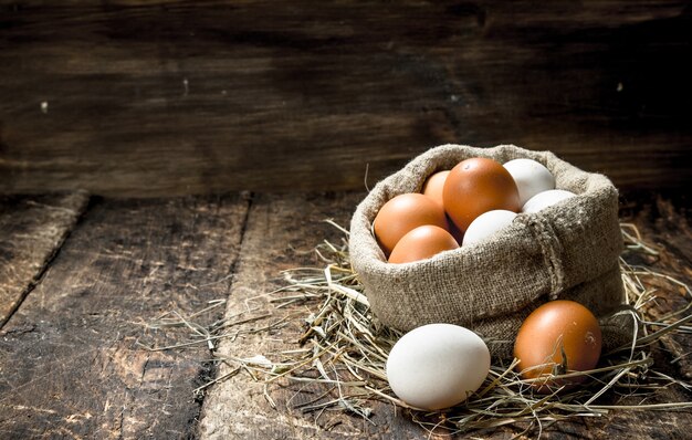 Verse kippeneieren in een oude zak op een houten achtergrond