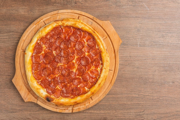 Foto verse klassieke pizza met tomatensaus mozzarella pittige chorizo paprika op een houten achtergrond