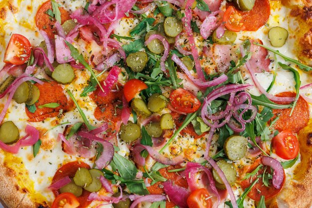 Verse klassieke pizza met tomatensous, uien en ingelegde komkommers.