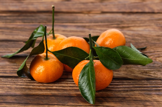 Verse kleine mandarines met bladeren op houten tafel