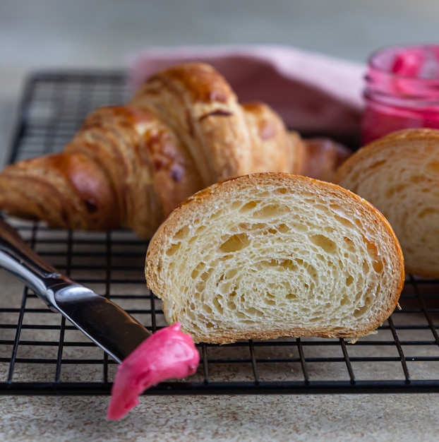 Verse knapperige croissants met roze honing op zwart metalen rooster.