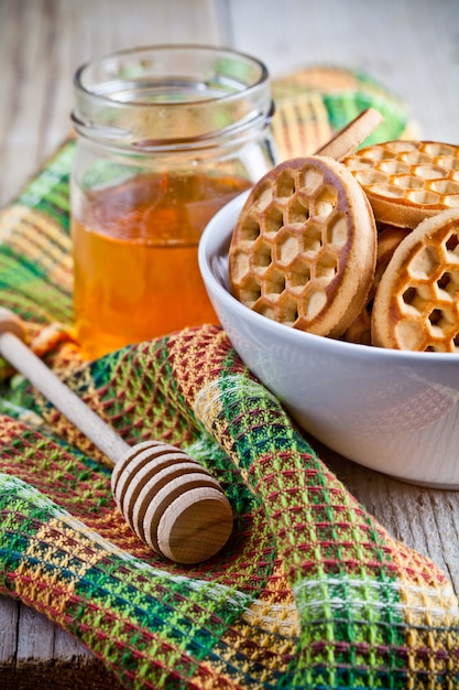 Verse koekjes in een kom, een tafelkleed en een honing