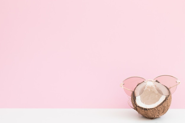 Verse kokosnoot met zonnebril op gekleurde achtergrond hallo zomer