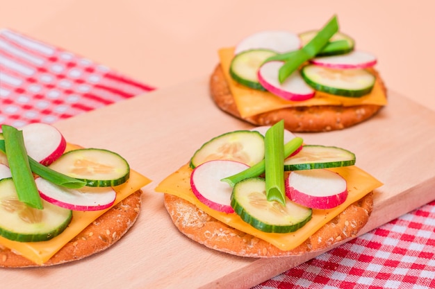 Verse komkommer en radijs met groene uien en kaas op knapperige cracker