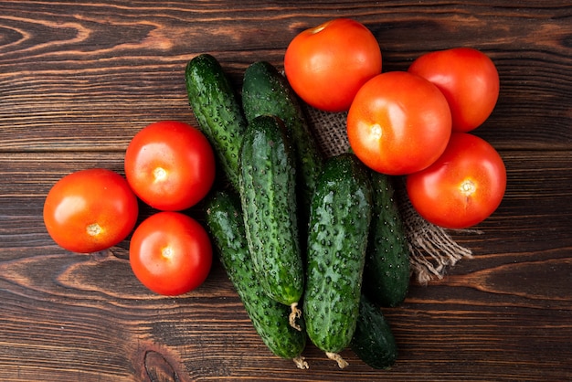 Verse komkommers en tomaten op donkere houten achtergrond.