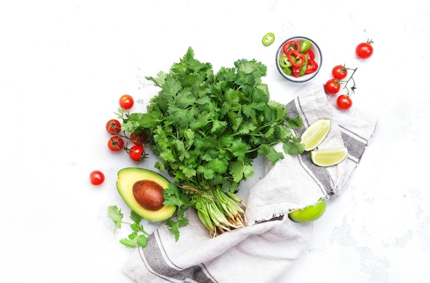 Verse koriander of koriander chili en jalapeno pepers avocado limoen en kerstomaatjes ingrediënten voor Mexicaanse pittige keuken Witte keuken tafel achtergrond bovenaanzicht