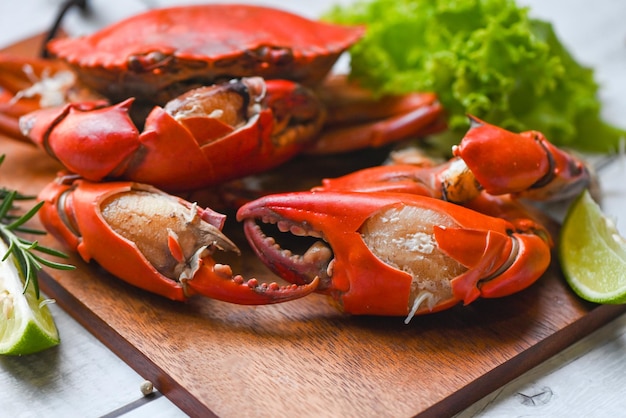 Verse krab op houten plank klauw krab koken voedsel zeevruchten plaat met kruiden specerijen citroen limoen salade gekookt of gestoomde krab rood in het restaurant