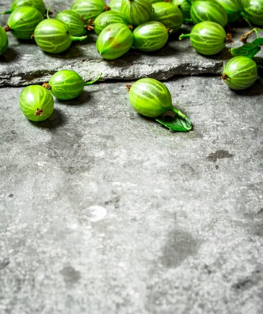 Verse kruisbessen met bladeren. Op de stenen tafel.