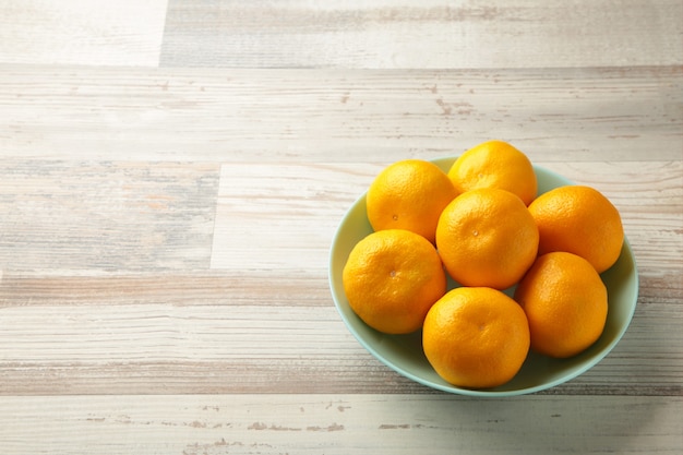 Verse mandarijn sinaasappelen fruit op muntkom op houten achtergrond. Bovenaanzicht.