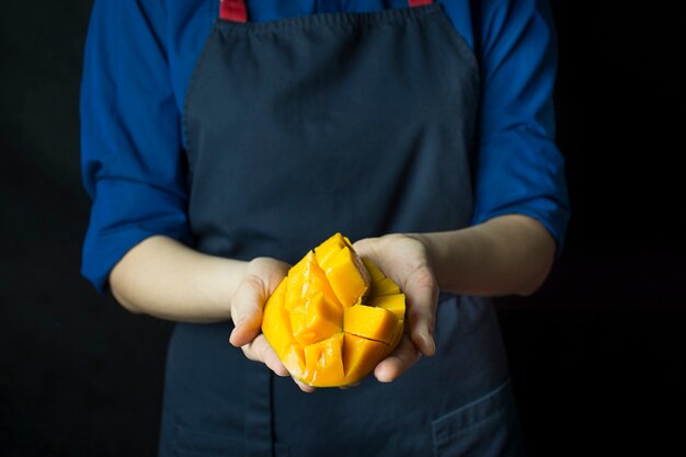 Verse mango in handen van de kok. Exotisch fruit. Rijpe mango. Gebalanceerd dieet.