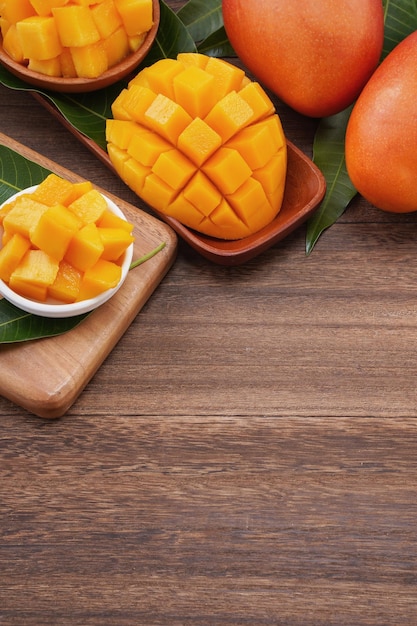 Verse mango mooi gehakt fruit met groene bladeren op donkere houten tafel achtergrond Tropisch fruit ontwerpconcept Plat lag Bovenaanzicht Kopieer ruimte