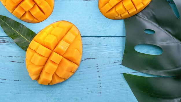 Foto verse mango mooie gehakte vruchten met groene bladeren op donkere houten tafel achtergrond tropisch fruit ontwerpconcept flat lay top view kopieerruimte