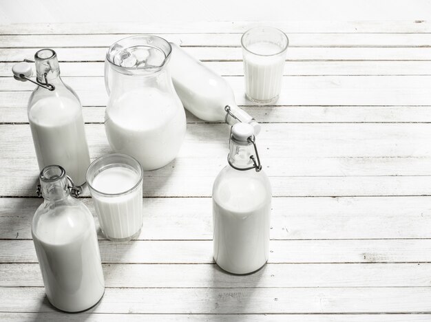 Foto verse melk in flessen op witte houten tafel.