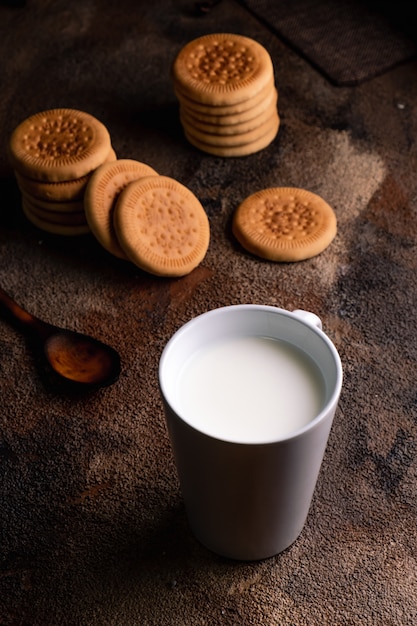 Verse melk met eigengemaakte koekjes op een houten lijst, donkere achtergrond.