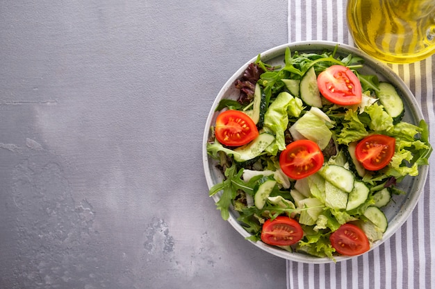 Verse mix van salades komkommers en verse tomaten op een bord. Gezond en dieetvoeding. Bovenaanzicht