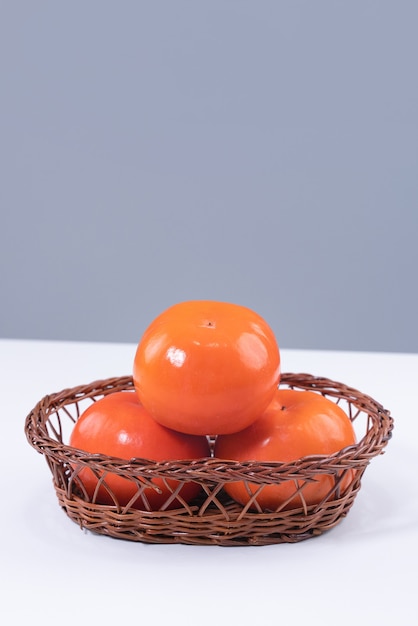Verse mooie gesneden zoete persimmon kaki geïsoleerd op witte keukentafel met grijs blauwe muur,