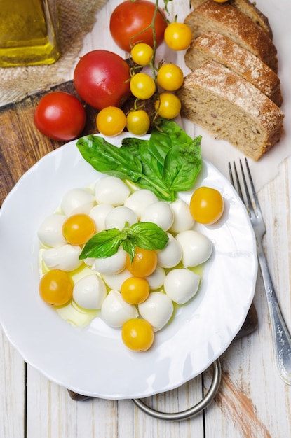 Verse mozzarella met gele tomaten en basilicum.