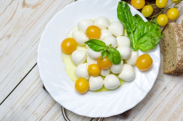 Verse mozzarella met gele tomaten en basilicum.