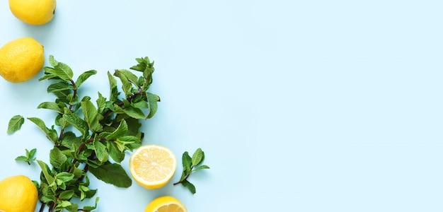 Verse munt en citroenen voor het maken van limonade op een blauwe tafel.