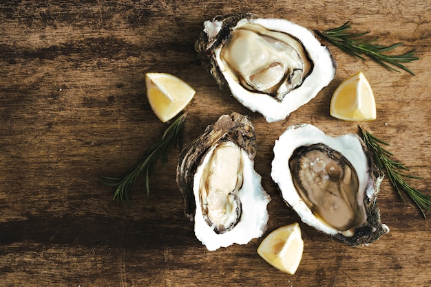 Verse net geopende oesters en schijfje citroen op rustieke houten tafel