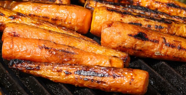 Verse nieuwe wortelen koken in een houtskoolgrill voor buiten met gietijzeren metalen rooster