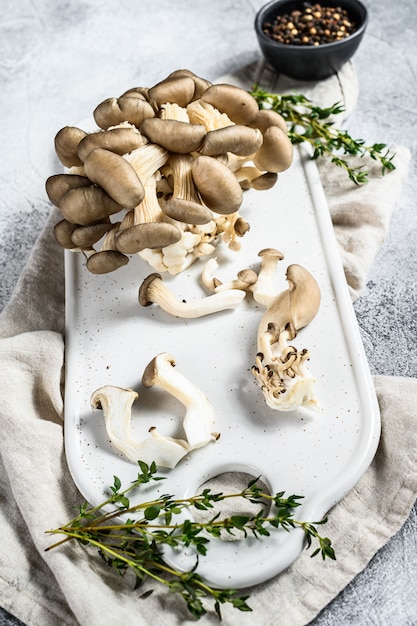 Foto verse oesterzwammen op een wit hakbord met tijm. bovenaanzicht