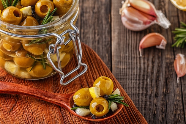 Verse olijven met rozemarijn, knoflook, citroen en olijfolie op rustieke houten achtergrond