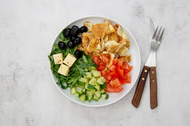 Verse omelet met verse gemengde groenten sla, tomaten, komkommer, olijven, kaas. Bovenaanzicht.