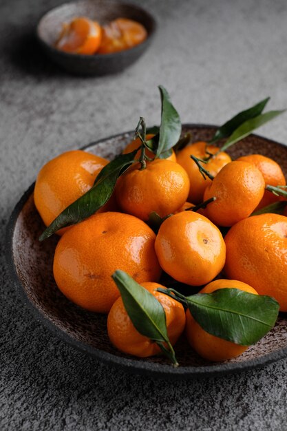 Verse oranje mandarijnen met groen blad bij ceramische plaat