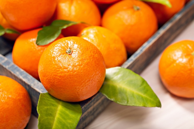 Verse oranje vruchten met bladeren op houten tafel