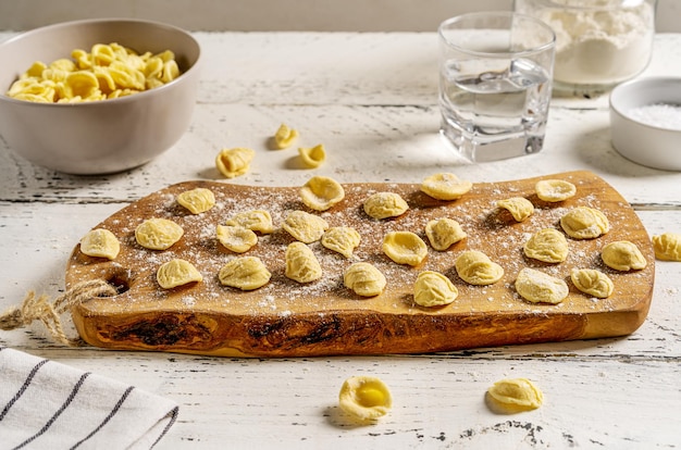 Verse Orecchiette is typisch Italiaanse pasta van Puglia Pasta op houten snijplank met ingrediënten
