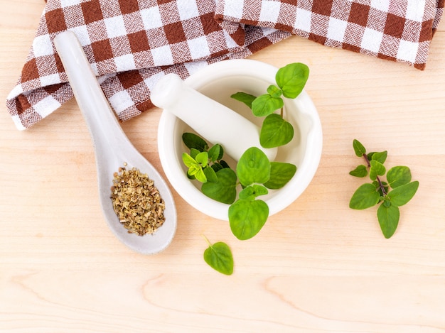 Verse oregano en droog met mortier op een houten achtergrond.