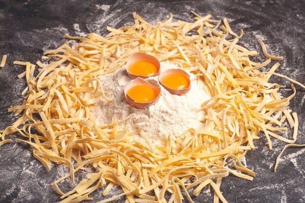 Verse pasta achtergrond zelfgemaakte Italiaanse fettuccine pasta gekookt in de huiskeuken met verse eieren en bloem op een houten achtergrond Italiaans eten en keuken concept hoge kwaliteit foto