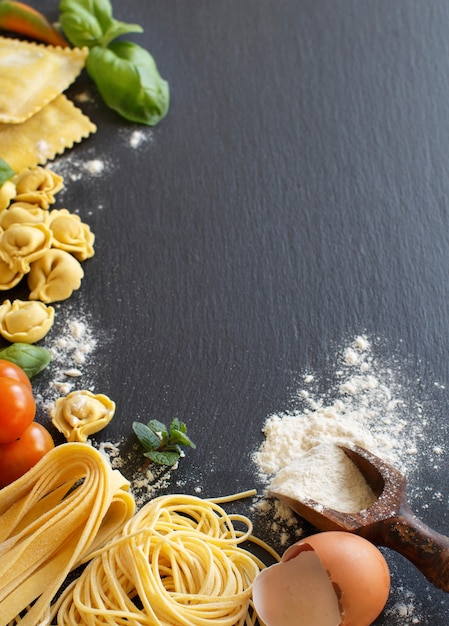 Verse pasta en ingrediënten op een donker bord bovenaanzicht