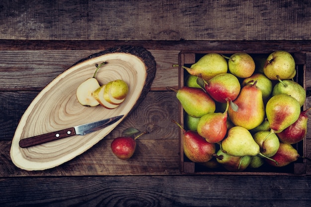 Verse peren met bladeren in een houten doos op houten.