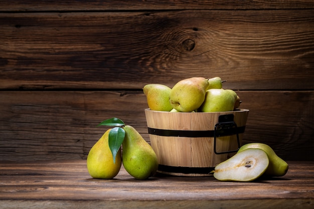 Verse peren met bladeren in een mand op houten achtergrond