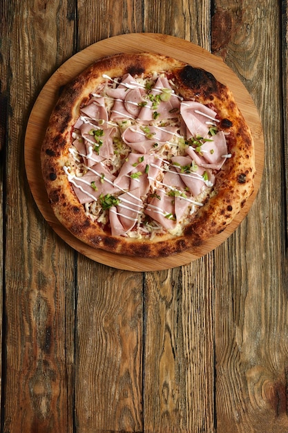 Verse pizza met ham en ananas op houten tafel in restaurant