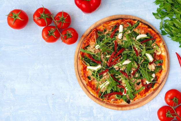 Verse pizza met kruiden en zongedroogde tomaten op grijze tafel