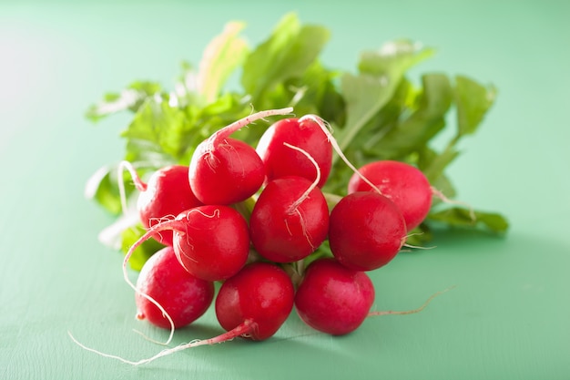 Verse radijs met bladeren over groene tafel