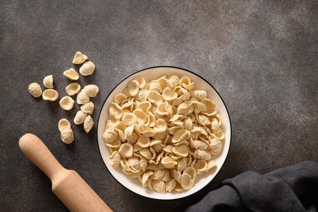 Verse rauwe apulische pasta orecchiette gemaakt van volkoren meel op een donker tafelblad