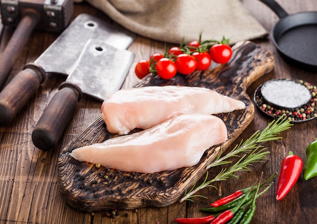 Verse rauwe biologische kipfilet borst op vintage bord met vleesbijlen