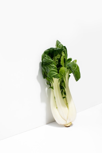 Verse rauwe Bok Choy-kool die langs de muur staat en een schaduw werpt, diagonaal vooraanzicht