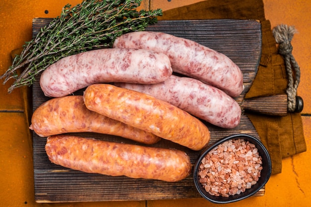 Verse rauwe braadworst en Chorizo-vleesworsten op houten bord Oranje achtergrond Bovenaanzicht