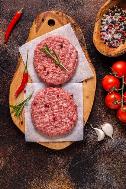 Verse rauwe gehakte zelfgemaakte grill beef hamburgers op houten snijplank, bovenaanzicht