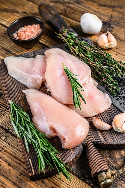 Verse rauwe gesneden gesneden kipfilet steaks op een houten snijplank met keukenmes. houten achtergrond. Bovenaanzicht.