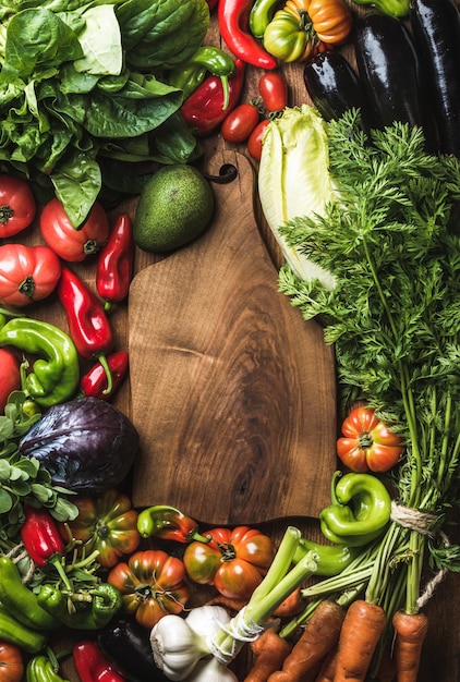 Verse rauwe groente-ingrediënten voor gezond koken of salade maken met rustieke houten plank in het midden bovenaanzicht kopieerruimte verticale compositie