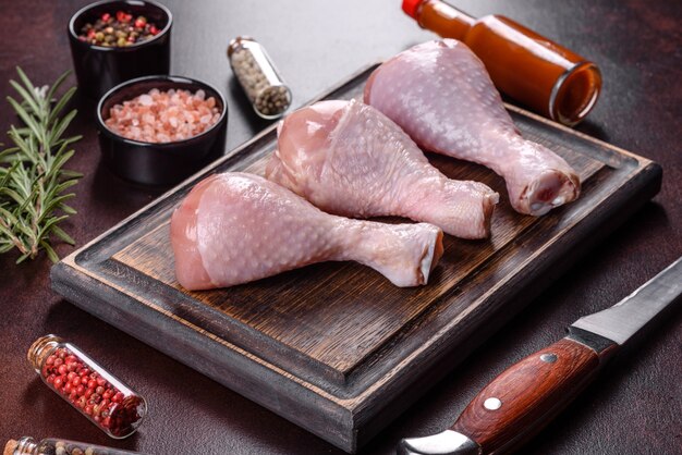 Verse rauwe kippenpoten met specerijen, zout en kruiden op een snijplank. Een gerecht klaarmaken om in de oven te bakken