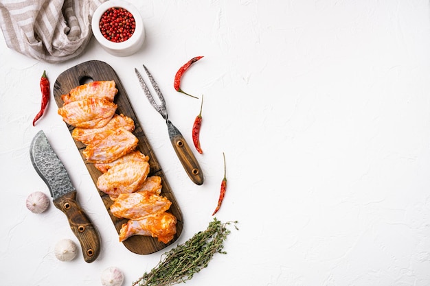 Verse rauwe kippenvleugels en ingrediënten voor bbq-sausset, op witte stenen tafelachtergrond, bovenaanzicht plat gelegd, met kopieerruimte voor tekst