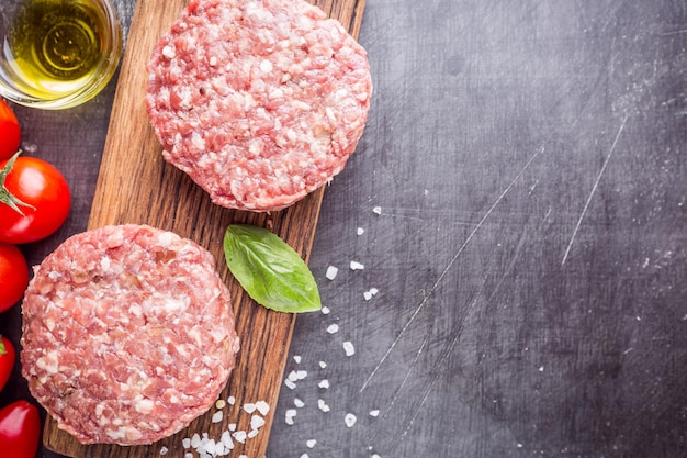 Verse rauwe Prime Black Angus beef burger pasteitjes op zwarte achtergrond. Bovenaanzicht.